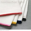 A group of white linen pocket squares with red, pink, yellow, navy and black hand rolled edges.